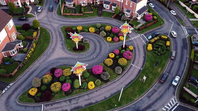 Aerial view presenting a repeating pattern of a suburban street with houses, cars, and a colorful roundabout, illustrating urban development and residential life from above