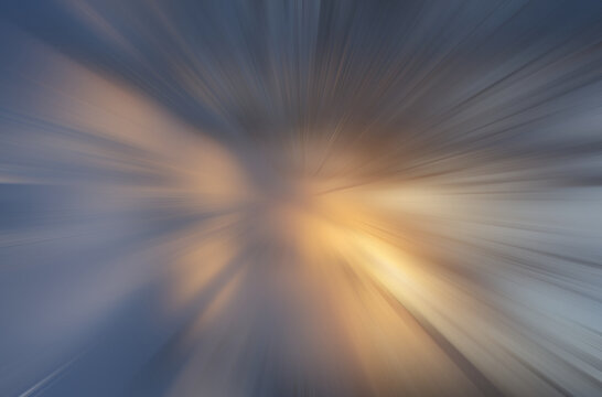 Abstrakcyjne tło z promienistym rozmyciem ruchu w niebiesko złotych barwach, dynamiczny efekt prędkości i energii.