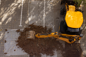 Excavator digging on paved ground top view