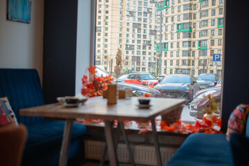 Blue sofas and a wooden table in the cafe with a view of the city of cars and houses. Blue and orange colors in the design. High quality photo