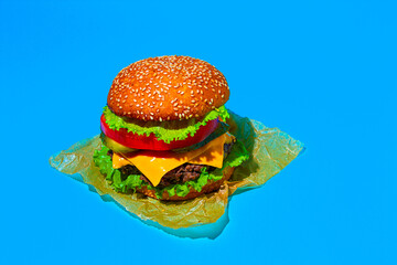 Juicy cheeseburger with fresh lettuce, tomato, and sesame seed bun on a bright blue background