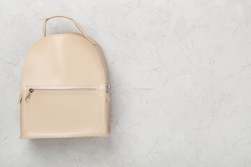 Female fashion beige backpack on concrete background, top view