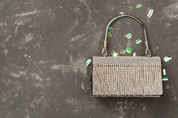 Handbag with beads on concrete background, top view