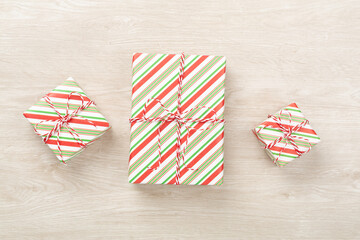 Striped Christmas gift boxes on wooden background, top view