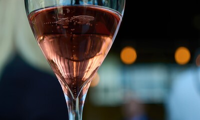 Closeup of a glass of rose champagne in restaurant. Sparkling wine, bubbles.
