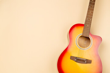 Bright acoustic guitar on color background, top view