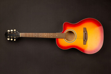 Bright acoustic guitar on color background, top view