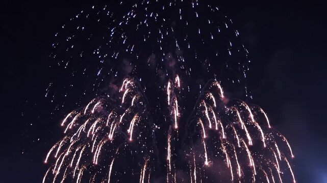 Vibrant blue and white fireworks exploding high in the night sky, illuminating the darkness with brilliant light 4k video