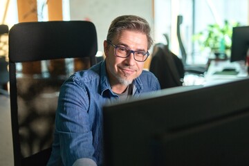 Businessman working with computer in office. Business lifestyle - casual middle aged man sitting at...