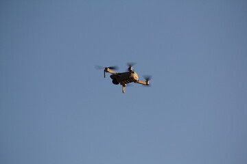 Quadrocopter with a professional camera flies in blue sky. Dron.