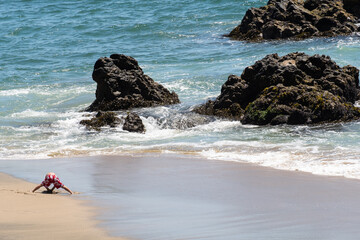 Nino jugando con arena en la playa, Valparaiso, Chile.
