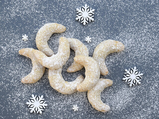 Vanilla rolls with walnuts - delicious Christmas cookies, homemade baking. White snowflakes around