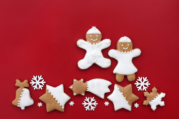 Decorated gingerbread cookies of various shapes on a red background, copy space for text. Christmas baking