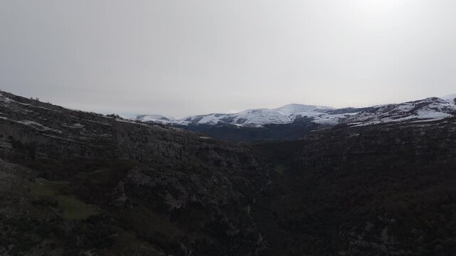 Mountains overlook cultivated slope in Valle del As&oacute;n - Here is a revised description, within the 147 character limit: A dark grey mountain landscape shows wooded slopes with natural vegetation and.