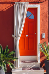 Fototapeta premium Red door on colorful house in Burano island, Italy