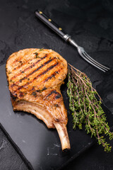 Savory bone in pork chop steak, beautifully charred and ready to impress at your next barbecue gathering.  black background. top view