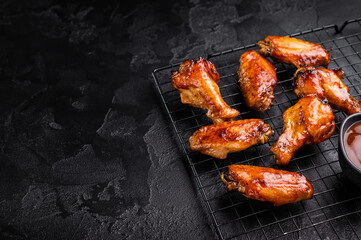 Mouthwatering BBQ chicken wings, coated in a rich sauce, perfect for finger-licking appetizers at any gathering. black background. top view