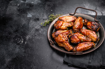 Savory grilled chicken wings smothered in tangy barbecue sauce, the ultimate treat for meat lovers and party enthusiasts. black background. top view