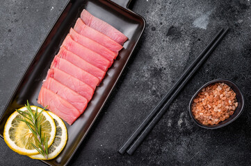 Premium quality tuna sashimi, expertly cut for maximum tenderness and taste, perfect for sushi enthusiasts. black background. top view