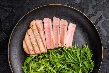 Succulent grilled tuna steak, showcasing vibrant color and rich taste, perfect for summer barbecues and elegant dinners. black background. top view