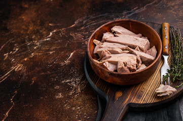 Sustainable tinned tuna fillet in a wooden bowl, promoting eco friendly eating without sacrificing taste. brown background. top view