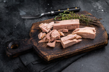 Chunky tinned tuna served on a wooden board, perfect for meal prep or easy weeknight dinners. black background. top view