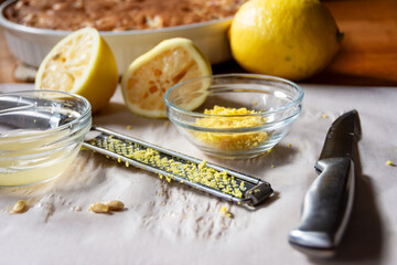 Preparing fresh lemon glaze: zest, juice, lemon rinds, and microplane near the baked cranberry cake. Natural, homemade food preparation.