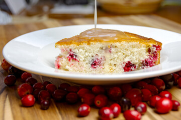 Served slice of homemade cranberry cake next to the lemon glaze, ready for the crucial pouring action shot. Sweet holiday dessert.
