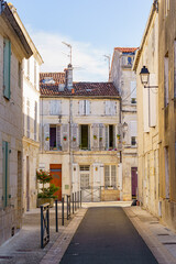 A narrow alleyway with a brick walkway and a few buildings in Saintes France. The buildings are white and have shutters on the windows