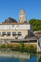 A beautiful city Saintes in France with a large clock tower and a river Charente running through it. The buildings are old and the sky is clear