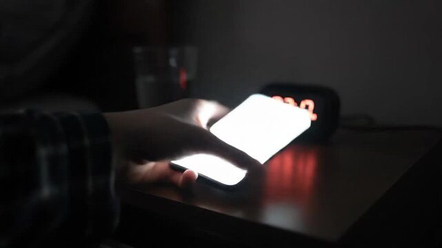 Alarm clock displays time in the darkness with water glass bedside