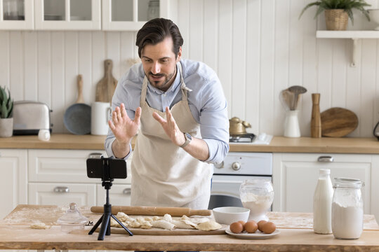 Confident man chef shooting culinary vlog in kitchen using phone