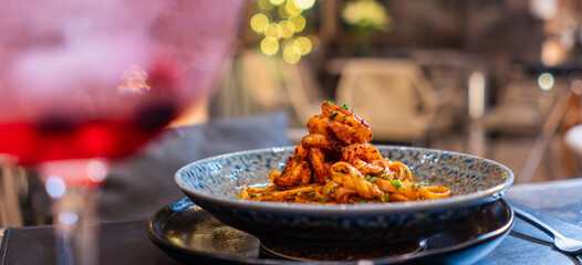 Pasta italiana con camarón y salsa boloñesa servida en plato azul