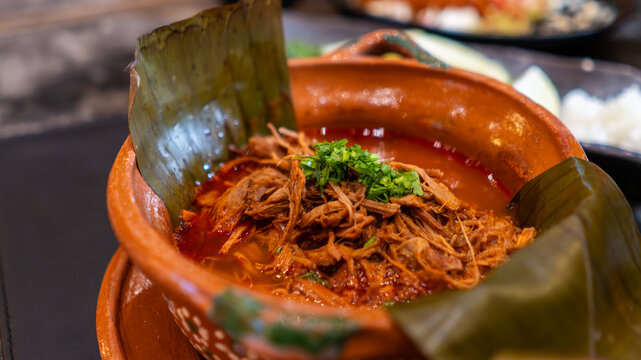 Barbacoa tradicional servida en plato de barro con hojas de pl&aacute;tano