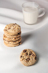 homemade chocolate chip and nut cookies stacked on a white surface