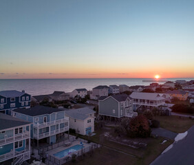 Sunset behind the pier with beachfront houses in Oak Island, North Carolina