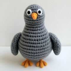 A handmade crochet bird with big eyes and an orange beak