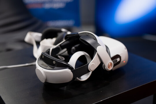 Virtual reality headset with comfort strap system and side controls placed on a dark surface during a technology event or immersive simulation setup