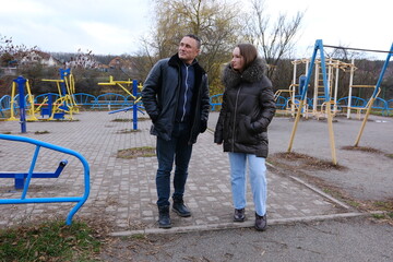 Family values father and daughter are walking in nature lake in fall in cold weather, drinking coffee, laughing, playing on playground, reminiscing about childhood, working out on horizontal bars.