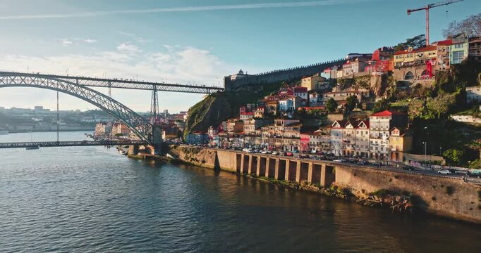 Portugal: Porto historic Ribeira district with colorful terraced houses along the Douro River. Bustling waterfront with cars and tourists enjoying the cityscape from bridge. Aerial view drone panorama