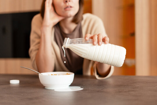 Woman spilling milk preparing messy breakfast cereal