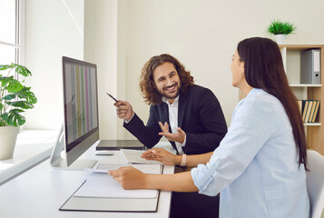 Young business people company employees man and woman having discussion analyzing company accounting looking to financial data at the desk. Coworkers working on workplace in office.