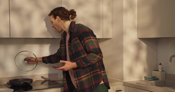 Morning light fills the cozy kitchen as a young man checks his phone, surrounded by fresh fruit