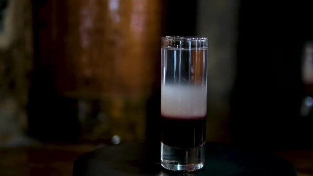 Row of colorful layered shots with bartender adding cream. High quality 4k footage