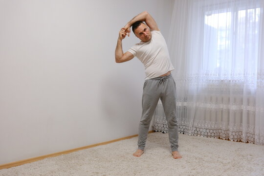 A middle-aged man stretching after waking up in a modern bedroom interior. High quality photo - Powered by Adobe