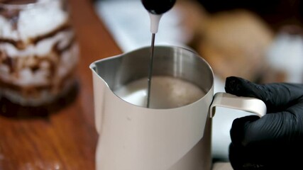 Barista steaming milk in a metal pitcher, Close-up of steamed milk being prepared with a frothing wand. High quality 4k footage