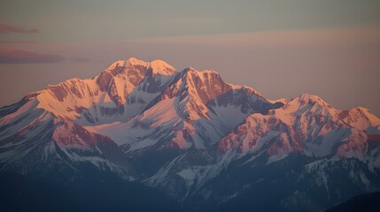 A breathtaking view of towering, snow-covered mountain peaks under a soft pastel sky.