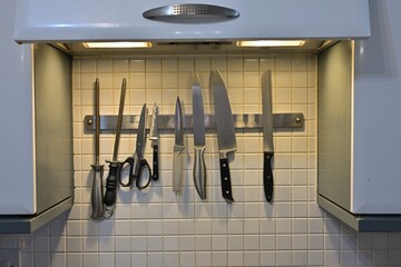 Magnetic knife strip with kitchen tools under hood lighting
