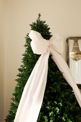 Elegant Christmas tree adorned with a large white bow in a cozy living room setting