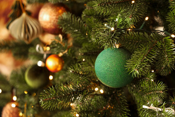 Festive green ornament hanging on a vibrant Christmas tree filled with lights and decorations